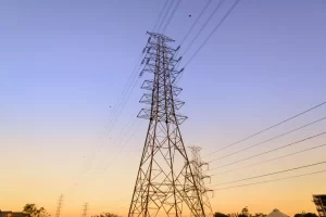 Linhas elétricas de alta tensão e torres de transmissão ao entardecer, cenário típico para discutir ampliação sistema GD I e cuidados para evitar erros em projetos e execução de rede