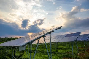 Campo com painéis solares fotovoltaicos instalados em estrutura metálica no campo, ao entardecer, com céu parcialmente nublado, usado no contexto de instalação e configuração para como corrigir grid zero 1 MW.
